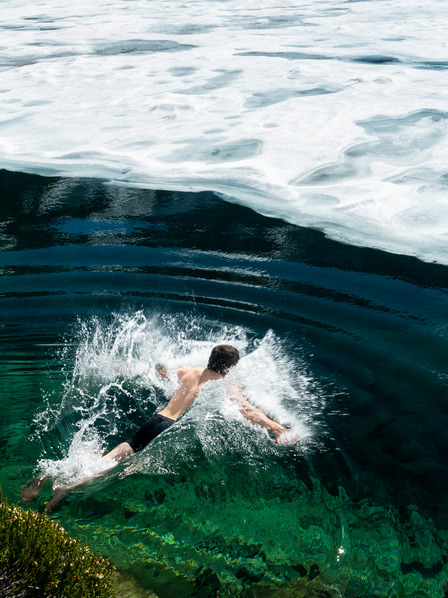 Person schwimmt in einem winterlichen See