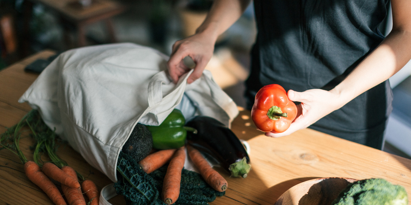 Frau packt ihr Gemüse nach dem Einkauf  aus der Stofftasche aus