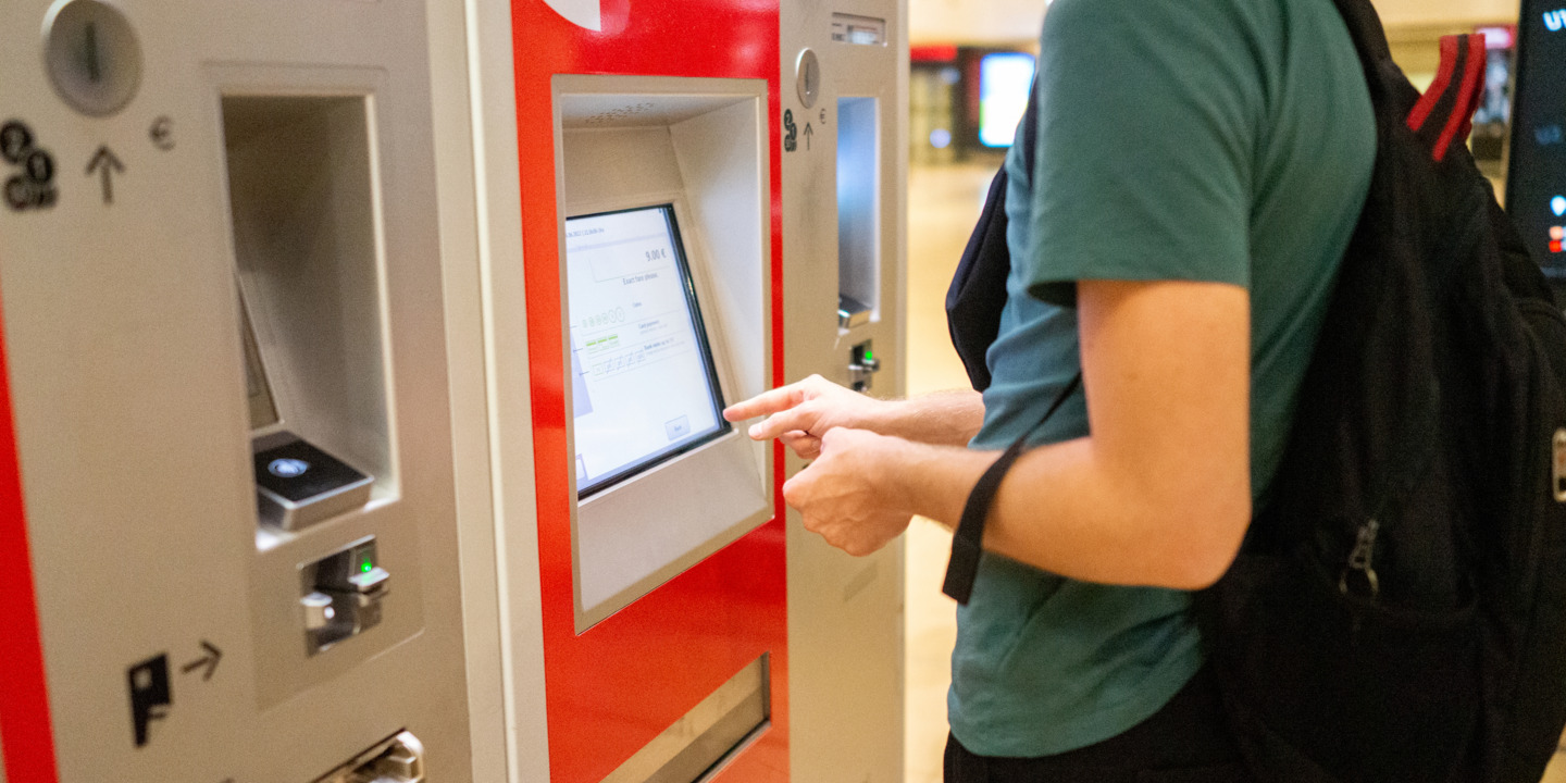 Teenager kauft eine Fahrkarte am Fahrkartenautomat