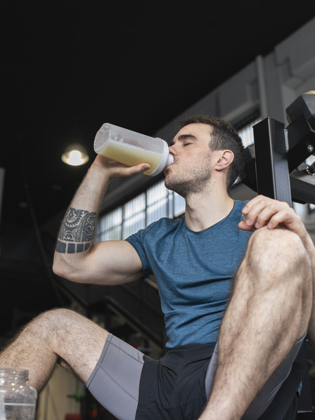 Mann in Sportkleidung trinkt Proteinshake