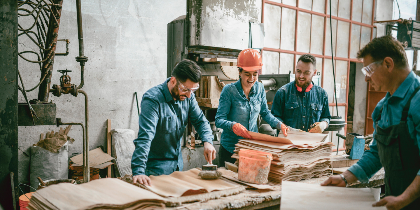 Vier Handwerker lachen zusammen in der Werkstatt