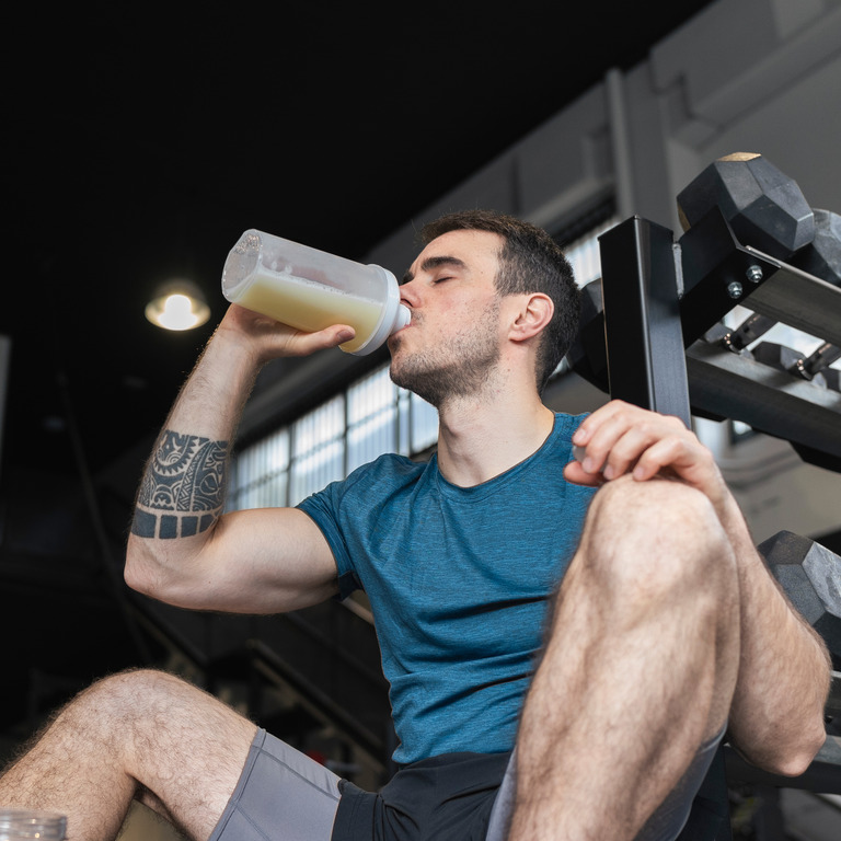 Mann in Sportkleidung trinkt Proteinshake
